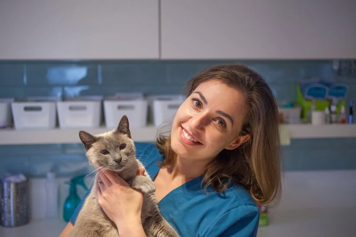 Dr. Demény Helga zâmbind, cu o pisică în brațe, în cabinet
